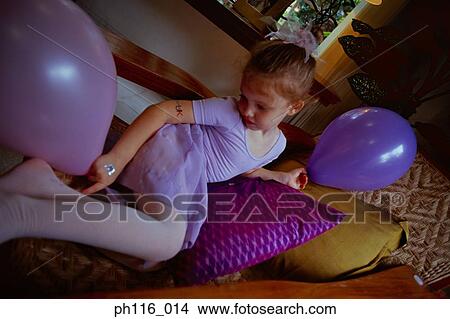 Young girl on sofa, holding balloons View Large Photo Image Picture - Young girl on sofa, holding balloons. Fotosearch