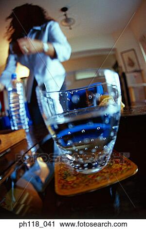 Stock Image - A glass, woman in the background. Fotosearch