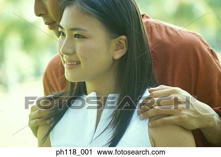 Couple in park, man standing behind woman View Large Photo Image Stock Image - Couple in park, man standing behind woman . Fotosearch