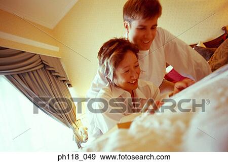 Couple on bed reading magazine View Large Photo Image Stock Photo - Couple on bed reading magazine. Fotosearch