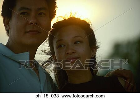 Couple outdoors, man with arm around woman's shoulder View Large Photo Image Stock Image - Couple outdoors, man with arm around woman's shoulder . Fotosearch