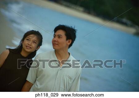 Stock Photo - Couple walking along beach. Fotosearch