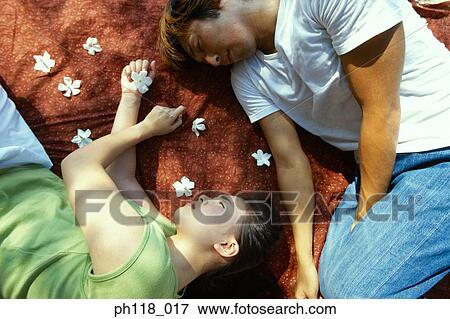 Stock Photo - Young couple lying on red fabric. Fotosearch