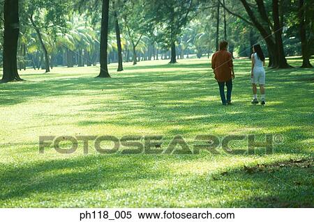Stock Photography - Young couple walking in park, rear view . Fotosearch