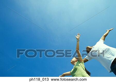 Young couple with hands open, low-angle view View Large Photo Image Stock Image - Young couple with hands open, low-angle view. Fotosearch