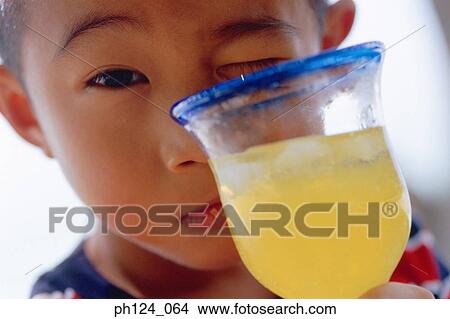 Close-up of a young Asian boy holding a glass of juice View Large Photo Image Picture - Close-up of a young Asian boy holding a glass of juice. Fotosearch