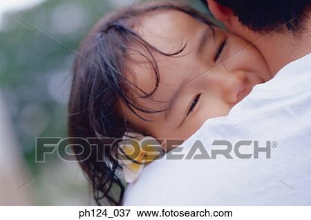 Stock Photo - Father hugging daughter, close-up. Fotosearch