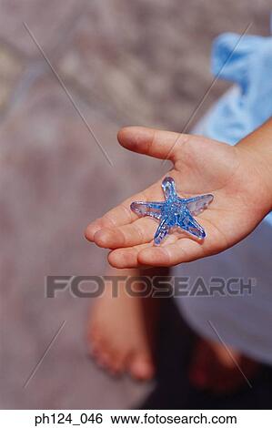 Stock Photograph - Hand holding a plastic star-shaped ornament. Fotosearch