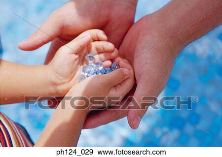 Hands of parent and child cupped, holding blue crystal-like ornaments View Large Photo Image Stock Photo - Hands of parent and child cupped, holding blue crystal-like ornaments. Fotosearch