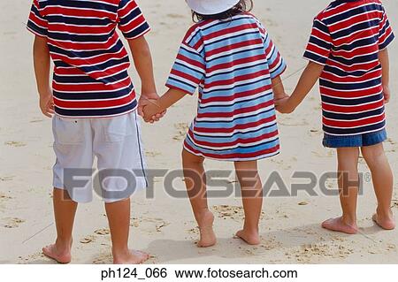 Rear view of 2 boys and a girl at the beach holding hands View Large Photo Image Stock Photograph - Rear view of 2 boys and a girl at the beach holding hands. Fotosearch