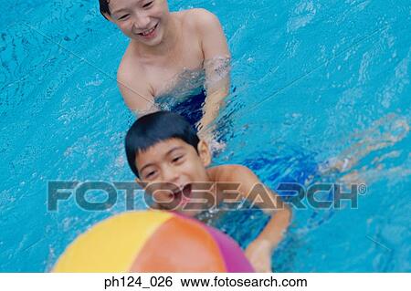 Two young boys playing beach ball in the pool View Large Photo Image Stock Photograph - Two young boys playing beach ball in the pool. Fotosearch