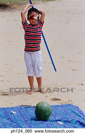 Young Asian boy blind folded holding a stick, watermelon on beach View Large Photo Image Stock Image - Young Asian boy blind folded holding a stick, watermelon on beach. Fotosearch