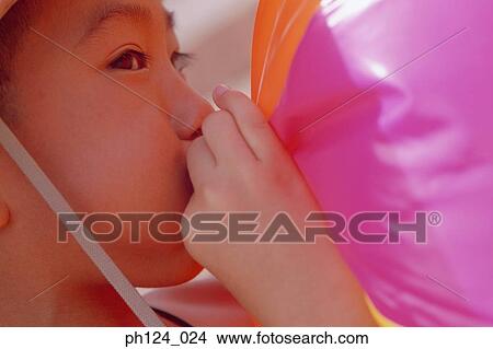 Picture - Young Asian boy blowing beach ball. Fotosearch