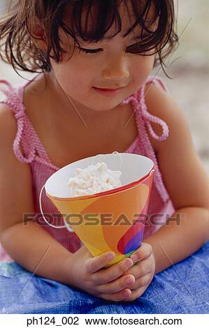 Stock Image - Young Asian girl holding a party hat. Fotosearch