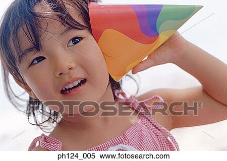 Young Asian girl holding a party hat close to her face View Large Photo Image Stock Photography - Young Asian girl holding a party hat close to her face. Fotosearch