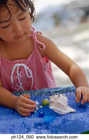 Young Asian girl playing with seashell and marbles View Large Photo Image Stock Image - Young Asian girl playing with seashell and marbles. Fotosearch