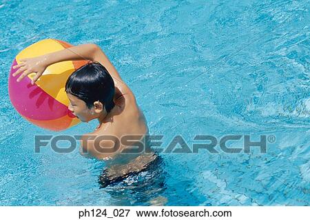 Stock Photo - Young boy playing beach ball in the pool. Fotosearch