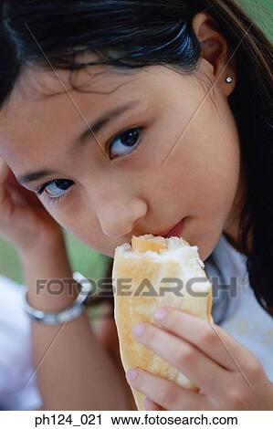 Young girl eating sausage bun, close-up View Large Photo Image Stock Image - Young girl eating sausage bun, close-up. Fotosearch