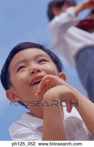 Portrait of a young Asian boy, low angle view View Large Photo Image Stock Image - Portrait of a young Asian boy, low angle view. Fotosearch