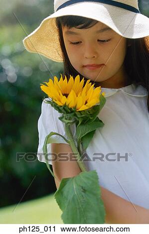 Stock Image - Portrait of a young girl with sunflower. Fotosearch