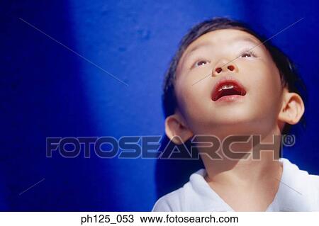 Stock Image - Young Asian boy looking up, close-up. Fotosearch