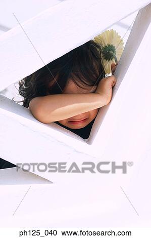 Stock Image - Young Asian girl resting on wall structure. Fotosearch