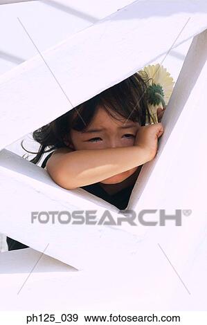 Stock Photo - Young Asian girl resting on wall structure. Fotosearch
