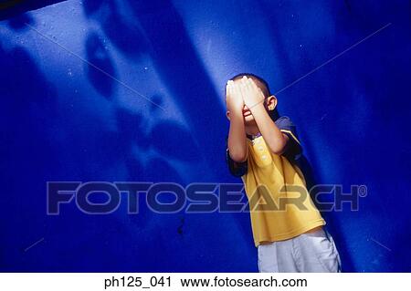 Stock Image - Young boy covering his face with hands. Fotosearch