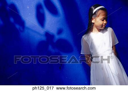 Stock Photo - Young girl leaning against blue wall. Fotosearch