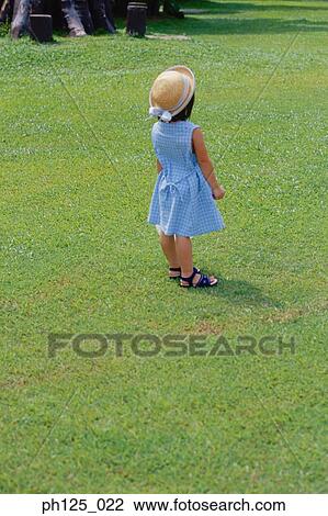 Young girl standing in green grass field, rear view View Large Photo Image Stock Image - Young girl standing in green grass field, rear view. Fotosearch