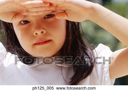 Stock Photography - Young girl with her hands on forehead, sheltering the sun. Fotosearch