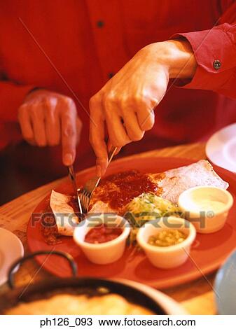 Stock Image - Man slicing Fajita with fork and knife. Fotosearch