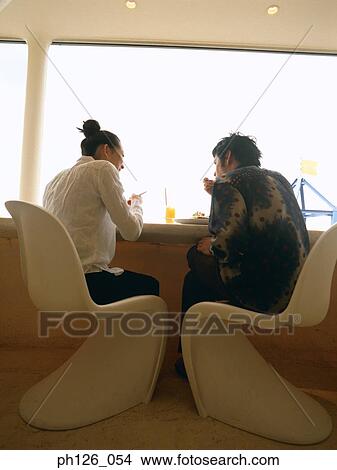 Young couple at a café, rear view View Large Photo Image Picture - Young couple at a café, rear view. Fotosearch