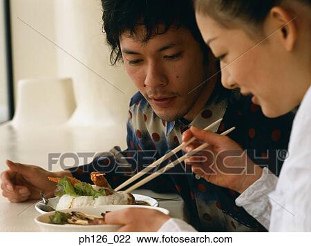 Stock Image - Young couple eating at a café. Fotosearch