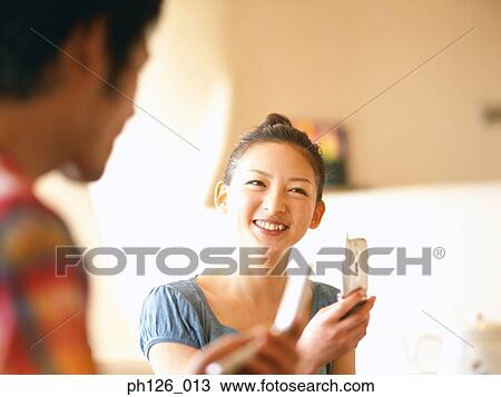 Young couple holding mobile phones View Large Photo Image Stock Image - Young couple holding mobile phones. Fotosearch