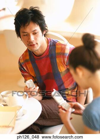 Stock Photo - Young couple holding mobile phones. Fotosearch