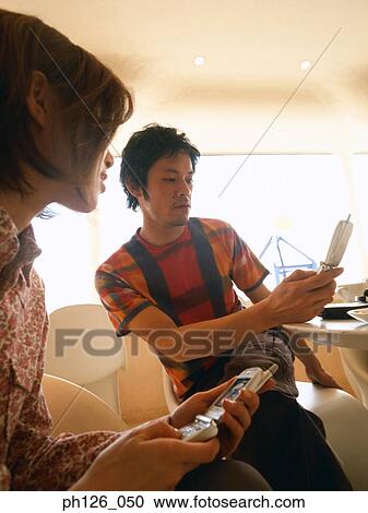 Young couple playing with mobile phones View Large Photo Image Stock Image - Young couple playing with mobile phones. Fotosearch