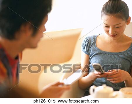 Stock Photography - Young couple playing with mobile phones. Fotosearch