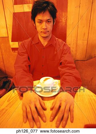 Young man and a cup of cappuccino on the table View Large Photo Image Stock Photo - Young man and a cup of cappuccino on the table. Fotosearch