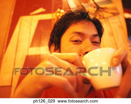 Stock Photo - Young man drinking from coffee cup. Fotosearch