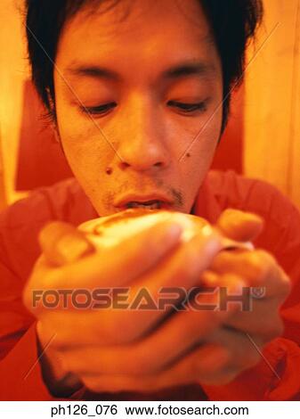Stock Photograph - Young man drinking from coffee cup, close-up. Fotosearch