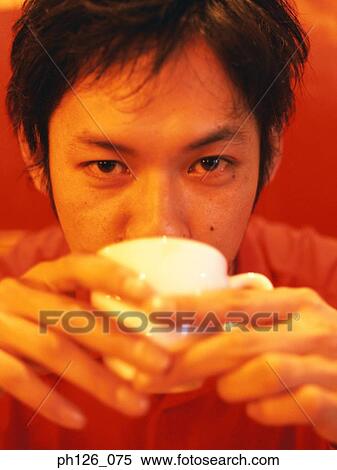 Stock Photography - Young man drinking from coffee cup, close-up. Fotosearch