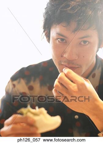 Stock Photo - Young man eating sandwich. Fotosearch