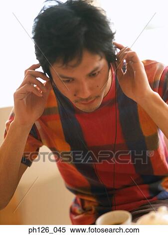 Young man listening to music with earphones View Large Photo Image Stock Photography - Young man listening to music with earphones. Fotosearch