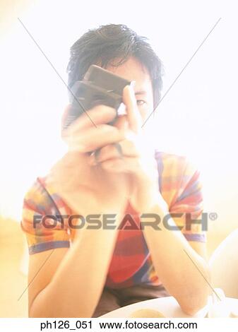 Stock Image - Young man playing with a camera. Fotosearch