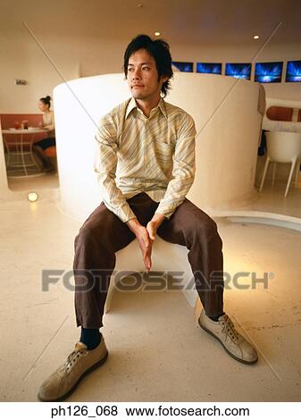 Young man sitting at a café View Large Photo Image Stock Photo - Young man sitting at a café. Fotosearch
