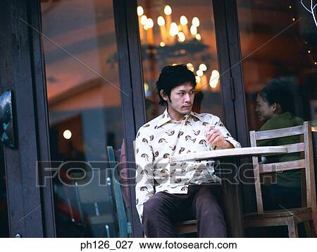Young man sitting outside sidewalk café View Large Photo Image Stock Photo - Young man sitting outside sidewalk café. Fotosearch