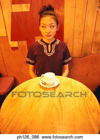 Young woman and a cup of coffee on the table, looking away View Large Photo Image Stock Photograph - Young woman and a cup of coffee on the table, looking away. Fotosearch