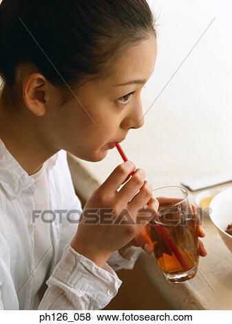 Young woman drinking from drinking straw View Large Photo Image Stock Photo - Young woman drinking from drinking straw. Fotosearch