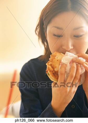 Young woman eating a burger View Large Photo Image Stock Photograph - Young woman eating a burger. Fotosearch